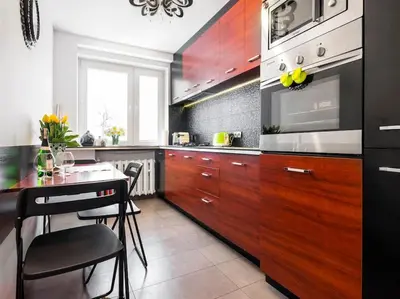 a kitchen with wooden cabinets and a table with chairs at Apartament Kolorowy in Kraków