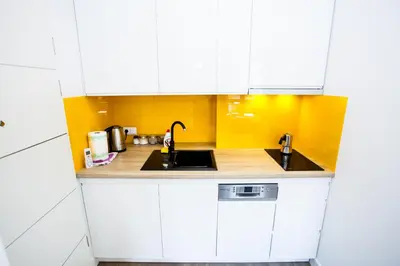 a small kitchen with white cabinets and a sink at Apartamenty SaltApart2 in Wieliczka