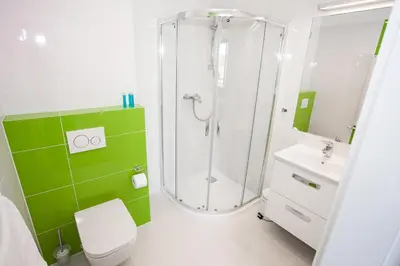 a green and white bathroom with a shower and a toilet at Apartamenty SaltApart2 in Wieliczka