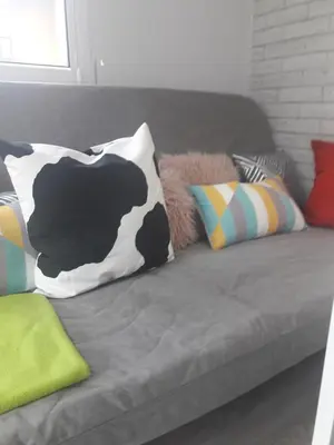 a gray couch with colorful pillows on it at Dobranocka - pokoje i całoroczne domki blisko Energylandii in Zator
