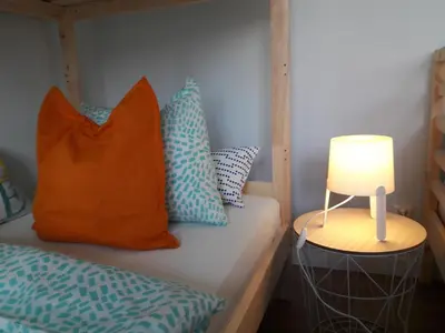 a bed with an orange pillow and a lamp on a table at Dobranocka - pokoje i całoroczne domki blisko Energylandii in Zator
