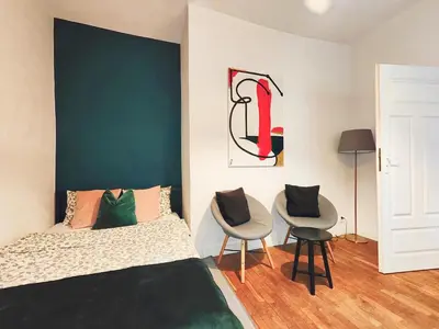 a bedroom with a bed and two chairs at A&K Apartment in Kraków