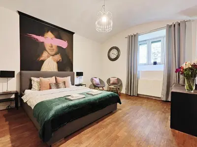 a bedroom with a bed with a large painting on the wall at A&K Apartment in Kraków