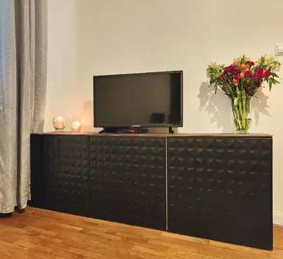 a television on a cabinet with a vase of flowers at A&K Apartment in Kraków