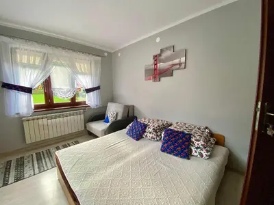 a bedroom with a bed and a chair and a window at Noclegi u Marii - Koninki in Poręba Wielka