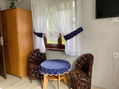 a bedroom with a bed with pillows and a chair at Noclegi u Marii - Koninki in Poręba Wielka