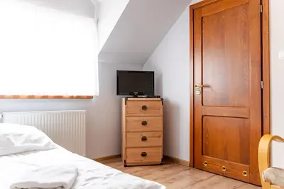 a bedroom with a bed and a television on a dresser at Stanica Hucuł in Sułkowice