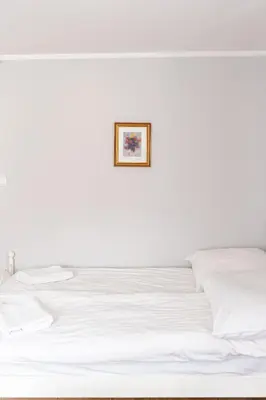 a bed with white sheets and a picture on the wall at Stanica Hucuł in Sułkowice
