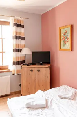 a bedroom with a bed and a television on a cabinet at Stanica Hucuł in Sułkowice