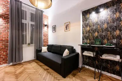 a living room with a black couch and a brick wall at DIETLA 99 APARTMENTS - IDEAL LOCATION - in the heart of Krakow in Kraków