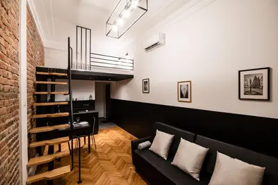 a living room with a black couch and a brick wall at DIETLA 99 APARTMENTS - IDEAL LOCATION - in the heart of Krakow in Kraków