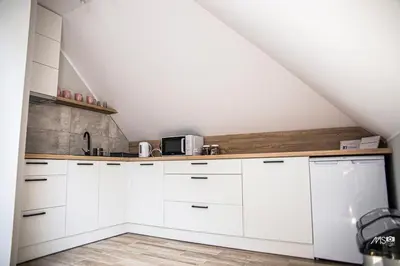 a white kitchen with white cabinets and a staircase at Domek u Mai in Zator