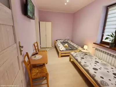 a room with two beds and a table and chairs at Domek u Mai in Zator
