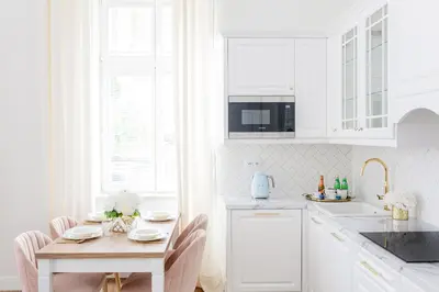 a kitchen with white cabinets and a wooden table at Apartament Golden Place in Kraków