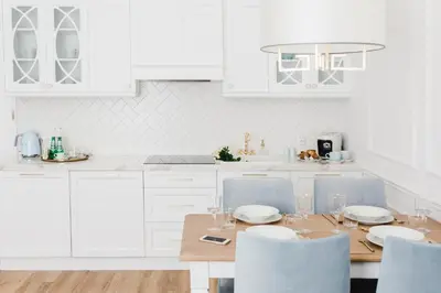 a white kitchen with a wooden table and chairs at Apartament Golden Place in Kraków