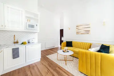 a living room with a yellow couch and a kitchen at Apartament Golden Place in Kraków