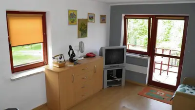 a living room with a television and two windows at Podelniska in Porąbka