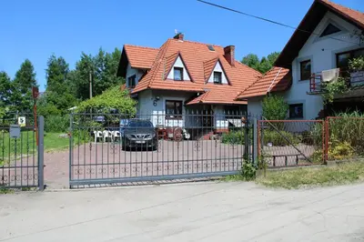 a fence in front of a house with a house at Podelniska in Porąbka