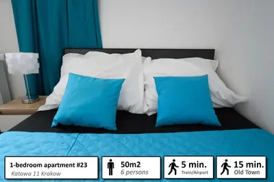 a bed with blue and white pillows on it at Station Apartments Katowa 11 in Kraków