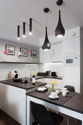 a kitchen with white cabinets and a table with chairs at Silver Apartment Old Jewish Quarter in Kraków