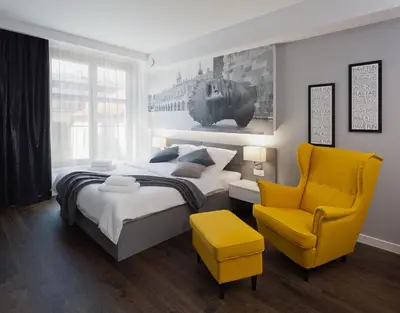 a bedroom with a bed and a yellow chair at City Point Apartment Old Jewish Quarter in Kraków