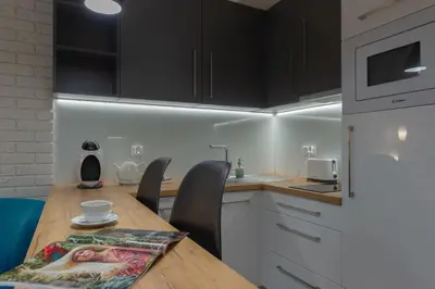 a kitchen with a wooden table and black cabinets at Native Apartments Augustiańska 24 in Kraków