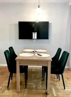 a wooden table with four green chairs and a television at Dom Gościnny Krystyna - ENERGYLANDIA, SPYTKOWICE, ZATOR in Spytkowice