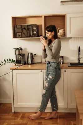 a woman standing in a kitchen drinking a cup of coffee at Dom Gościnny Krystyna - ENERGYLANDIA, SPYTKOWICE, ZATOR in Spytkowice