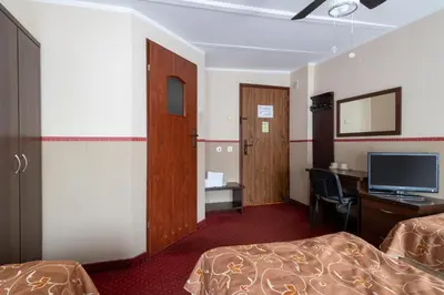 a hotel room with two beds and a desk and a television at Pensjonat Stańczyk in Kraków