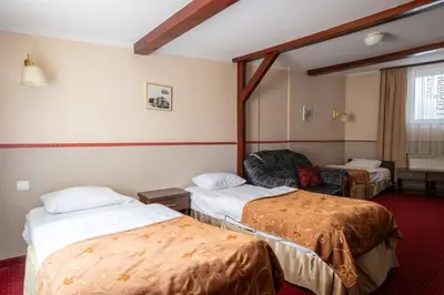 a hotel room with two beds and a chair at Pensjonat Stańczyk in Kraków