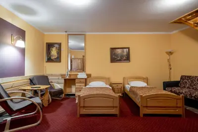 a room with two beds and a table and a couch at Pensjonat Stańczyk in Kraków