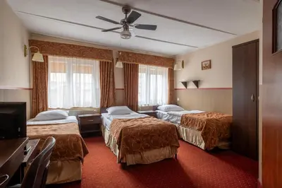 a hotel room with two beds and a ceiling fan at Pensjonat Stańczyk in Kraków