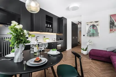 a dining room and living room with a black table and chairs at Moss Apartment in Kraków