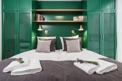 a green bedroom with a large bed with towels on it at Moss Apartment in Kraków