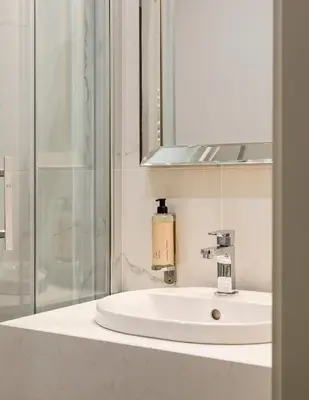 a bathroom sink with a mirror and a soap dispenser at Moja apartments in Kraków
