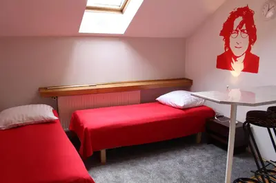 a room with two beds and a table and a window at Cracow Old Town Guest House in Kraków