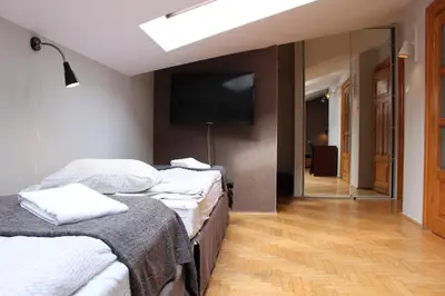 a bedroom with two beds and a flat screen tv at Cracow Old Town Guest House in Kraków