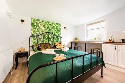 a green bed in a small room with a kitchen at Lu Apartments in Oświęcim