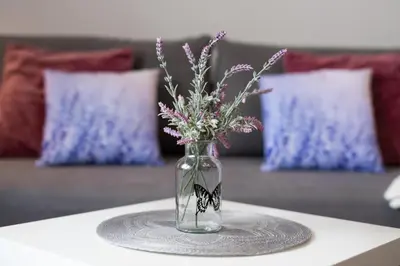 a glass vase with flowers and a butterfly on a table at Lu Apartments in Oświęcim