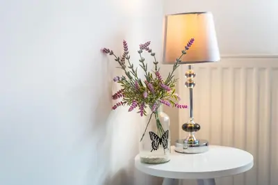a table with a lamp and a vase with flowers at Lu Apartments in Oświęcim