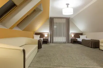 a hotel room with two beds and a couch at Hotel Górski Raj in Koninki