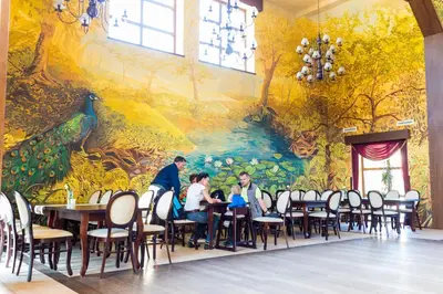 people sitting at tables in a dining room with a mural at Hotel Górski Raj in Koninki