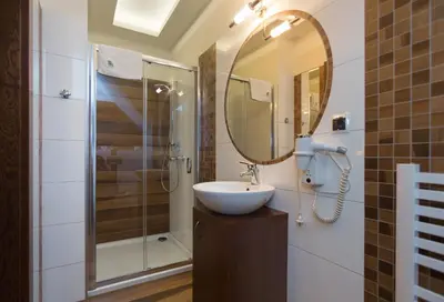 a bathroom with a sink and a shower and a mirror at Hotel Górski Raj in Koninki