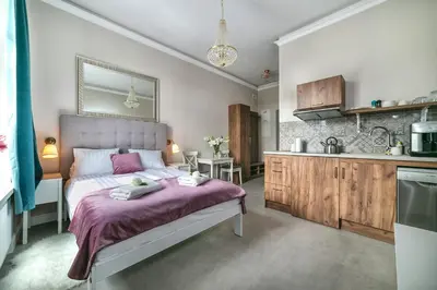 a bedroom with a large bed and a kitchen at Apartamenty Wrona | Wrona Apartments in Kraków