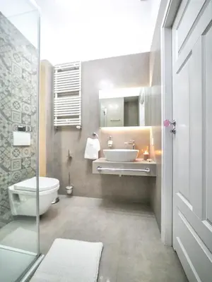 a bathroom with a sink and a toilet and a mirror at Apartamenty Wrona | Wrona Apartments in Kraków