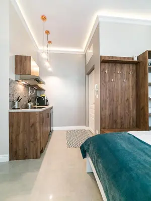 a bedroom with a bed and a kitchen at Apartamenty Wrona | Wrona Apartments in Kraków