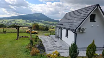 a white house with a car parked in a field at Agrorelax - Kasina Wielka in Kasina Wielka