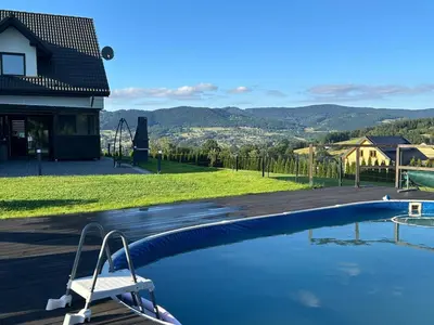 a swimming pool with a chair next to a house at Holiday home Limanowa in Limanowa