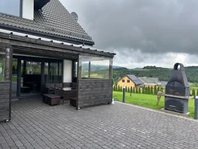 a building with a patio with a grill in a field at Holiday home Limanowa in Limanowa