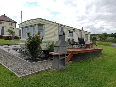 a mobile home with a deck and a house at Leśny Zakątek Radocza in Radocza